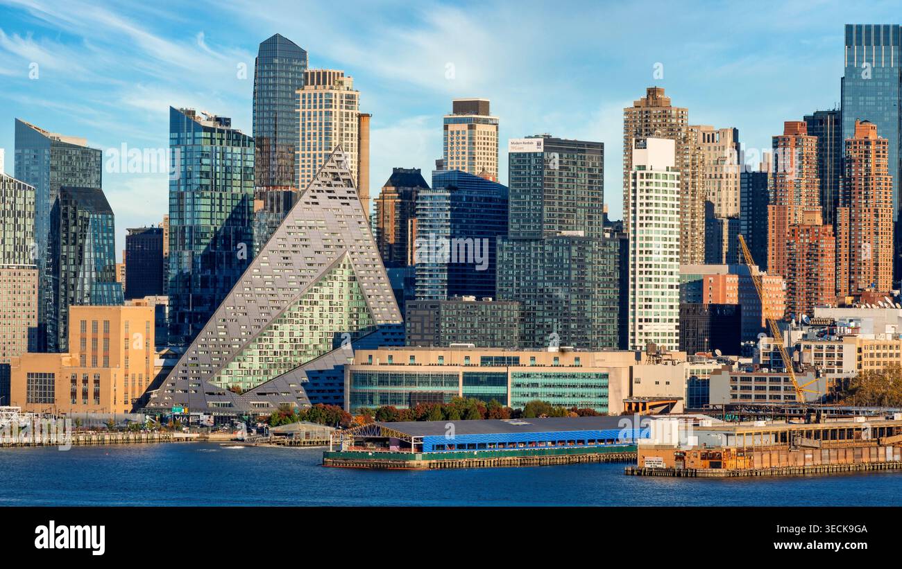 Das Bild fängt die markante Silhouette der Skyline von Manhattan mit einem einzigartigen dreieckigen Gebäude im Vordergrund ein. Hohe Wolkenkratzer umrahmen die Szene Stockfoto