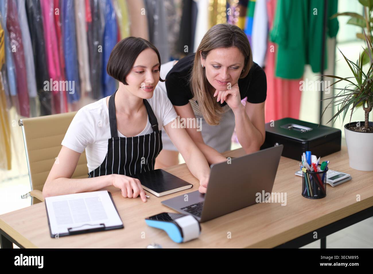 Modedesigner arbeiten in einem hellen Studio zusammen, planen neue Designs und diskutieren kreative Ideen am Arbeitsplatz Stockfoto