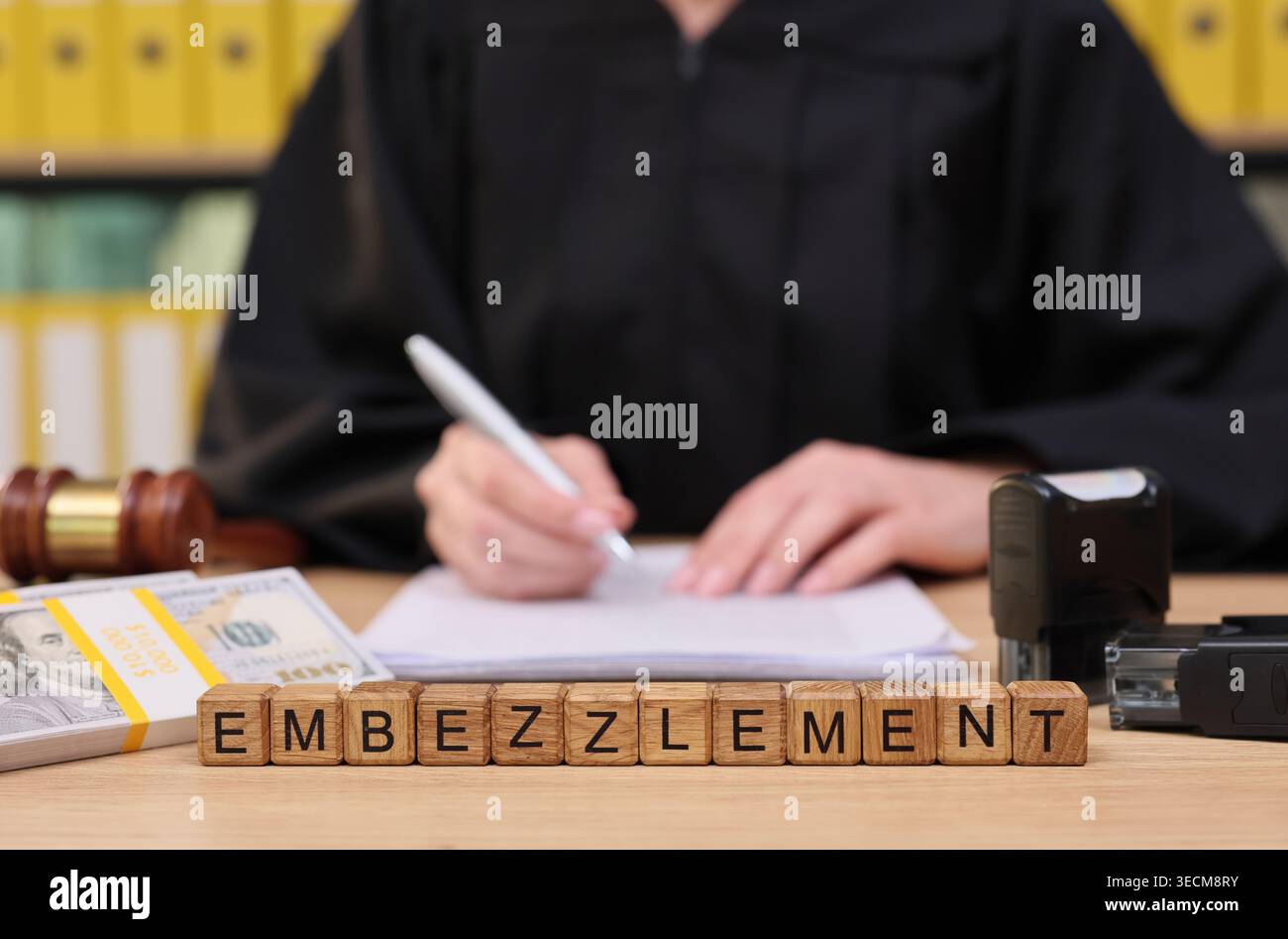 Richter, der den Fall über Veruntreuung überprüft, während er an einem hölzernen Schreibtisch sitzt, mit juristischen Dokumenten und einem Hammer im Gerichtssaal Stockfoto