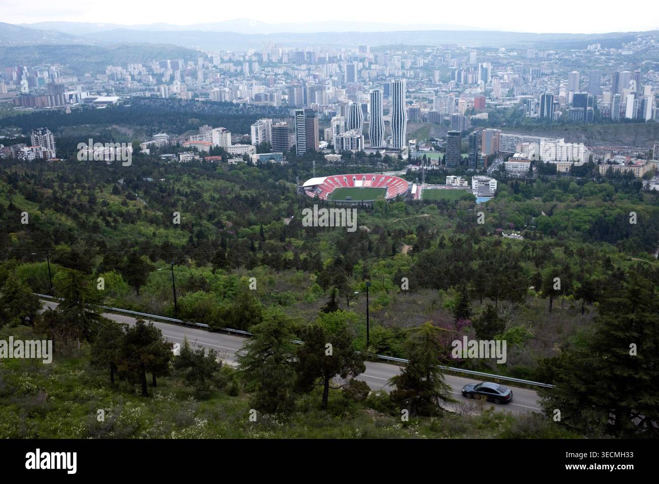 Eine Skyline der Stadt mit zahlreichen Gebäuden überblickt einen üppig grünen Park mit einem Stadion. Stockfoto