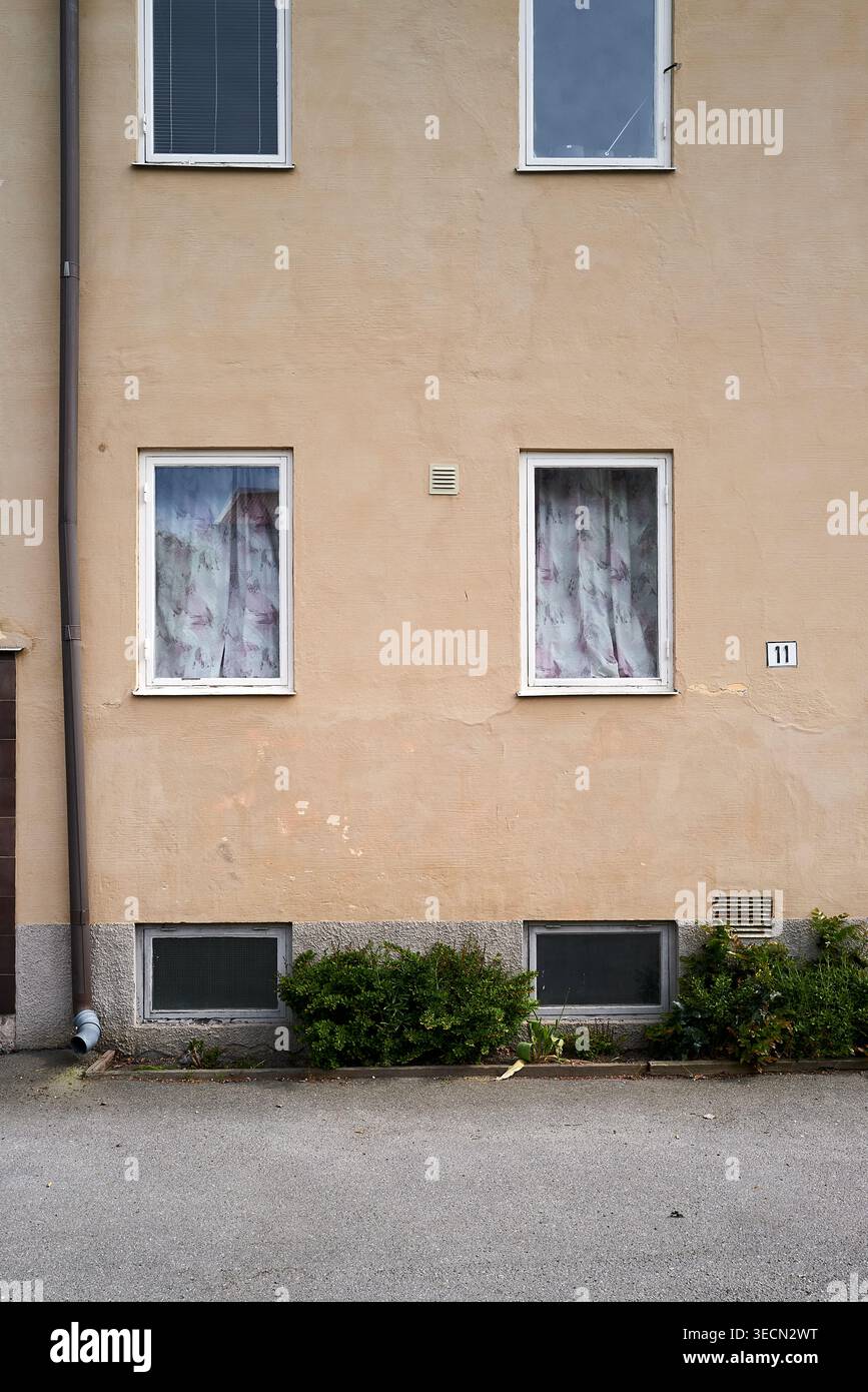 Einfache, schlichte Gebäudefassade mit zwei Fenstern und überdachten Vorhängen für Privatsphäre. Nynashamn, Stockholmer County, Schweden, 25. Mai 2025 Stockfoto