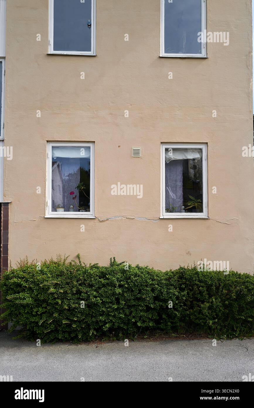 Einfache, schlichte Gebäudefassade mit zwei Fenstern und überdachten Vorhängen für Privatsphäre. Nynashamn, Stockholmer County, Schweden, 25. Mai 2025 Stockfoto