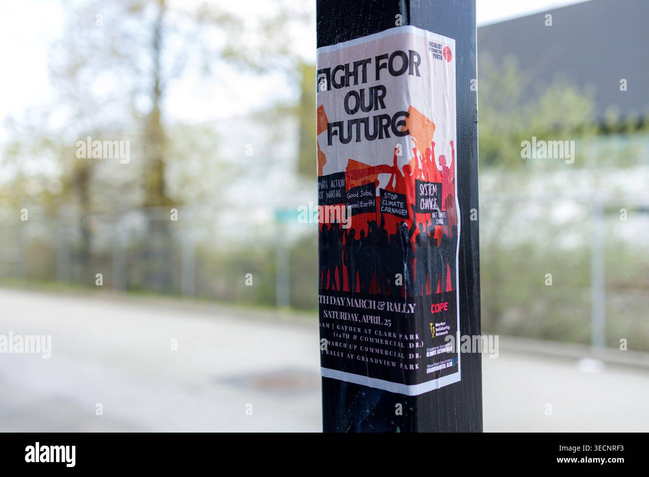 Vancouver, Kanada - 17. April 2026: Ein Kampf für unsere Zukunft der Welttag-Rallye-Poster wickelt sich um einen schwarzen Straßenmast neben einem Maschendrahtzaun und einer Schiene Stockfoto