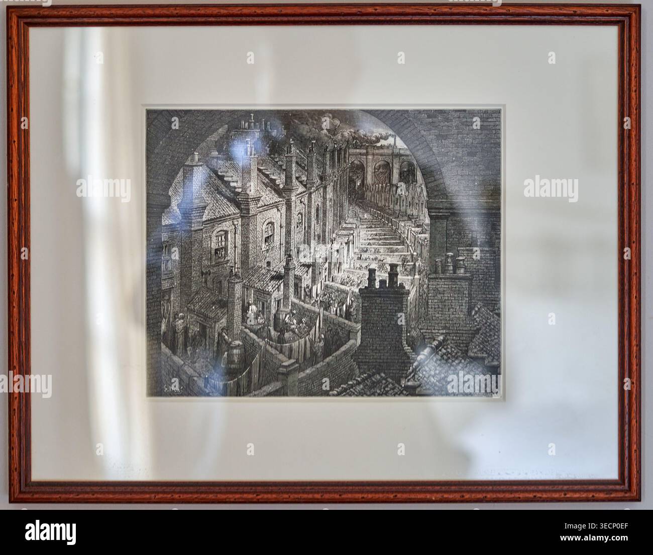 Eine gerahmte Schwarz-Weiß-Radierung, die eine dichte industrielle viktorianische Stadtszene zeigt, betrachtet durch einen Ziegelbogen. Das detaillierte Kunstwerk zeigt Stockfoto
