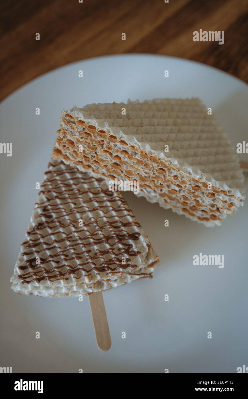 Zwei Waffelkuchen mit Kondensmilch auf einem Stock auf einem weißen Teller. Hausgemachtes Dessert, flach gelegt Stockfoto