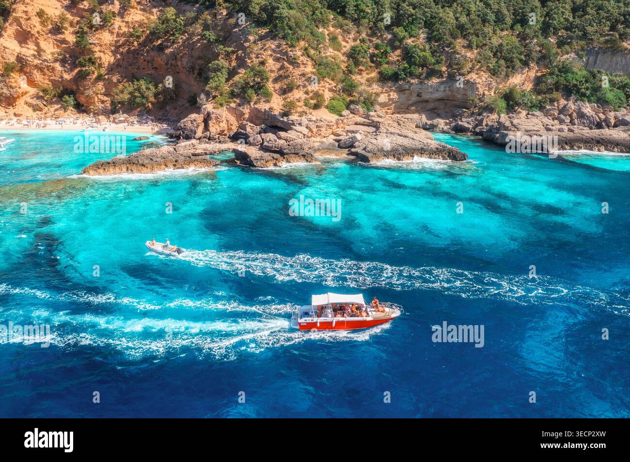 Blick aus der Vogelperspektive auf das rote Schnellboot, das türkisfarbene Meer und den Sandstrand. Sommer Stockfoto