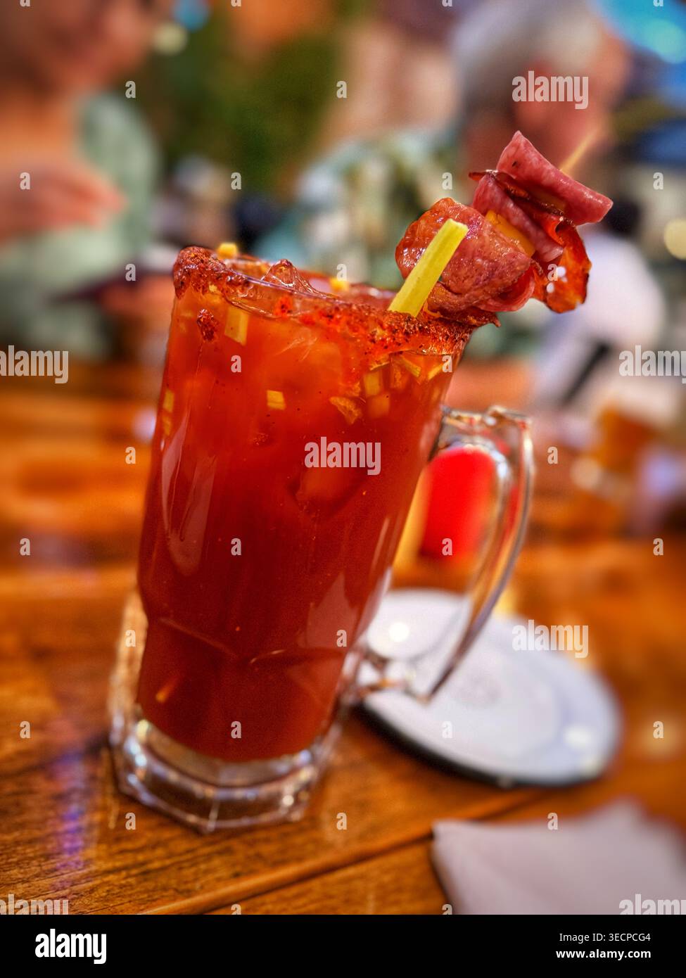 Ein erfrischender Bloody Mary Cocktail, serviert in einem Glasbecher mit gesalzenem Rand und einer raffinierten Garnitur aus Fleischspießen und Sellerie Stockfoto