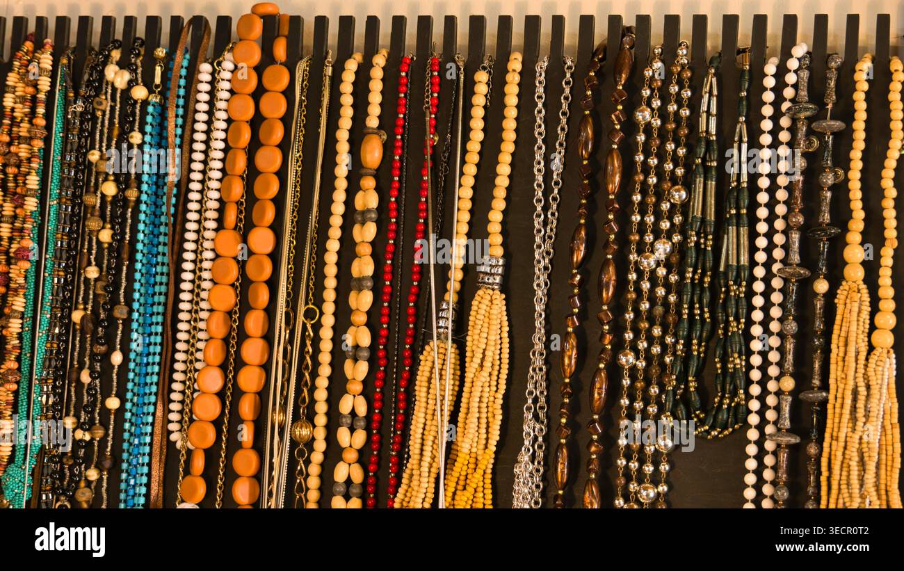 Farbenfrohe Halsketten aus zweiter Hand und Perlenschmuck auf einem schwarzen Ladenständer Stockfoto