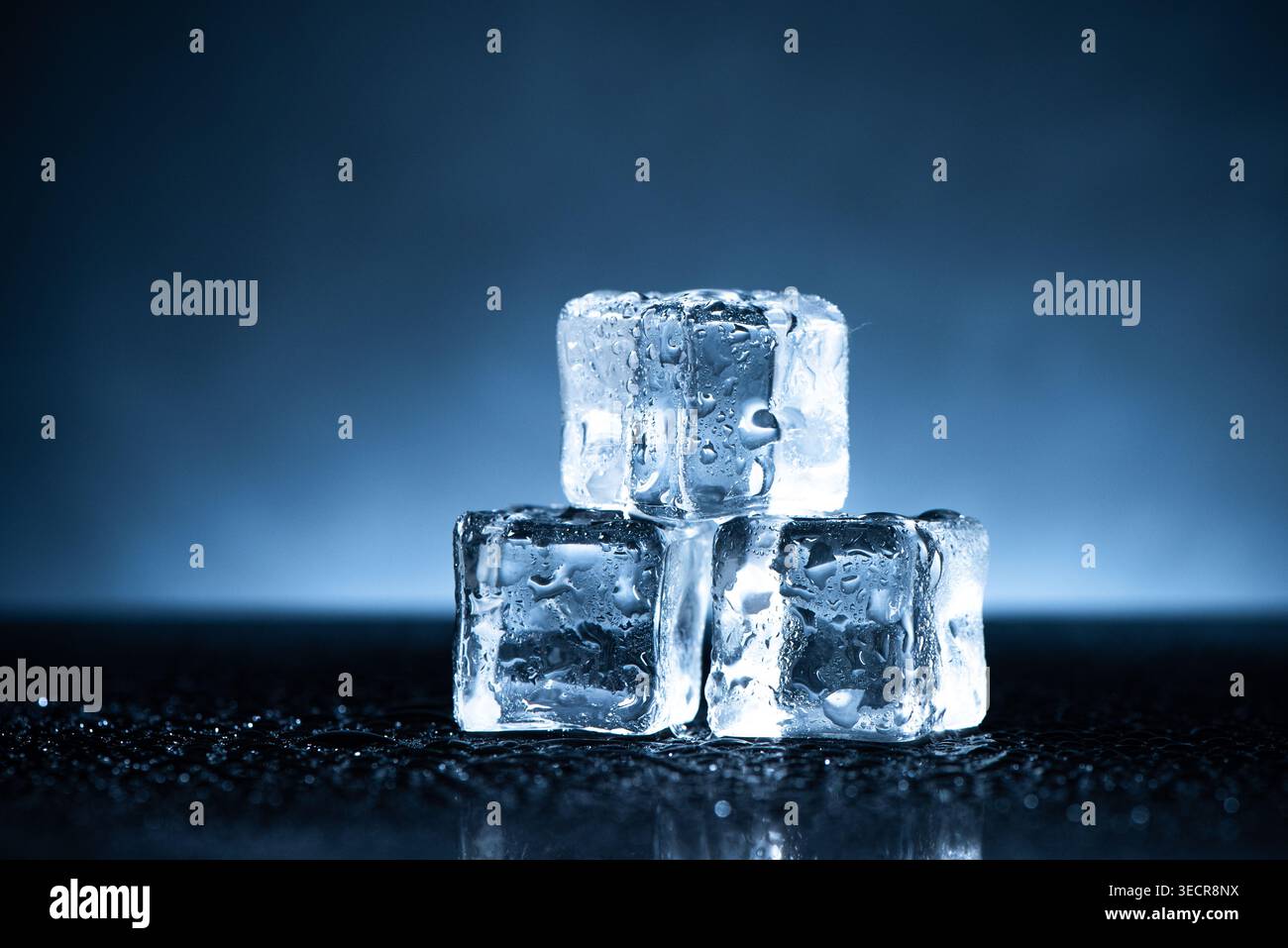 Eiswürfel schmelzen, erfrischende kalte Wassertröpfchen bilden sich auf einer dunklen Oberfläche Stockfoto