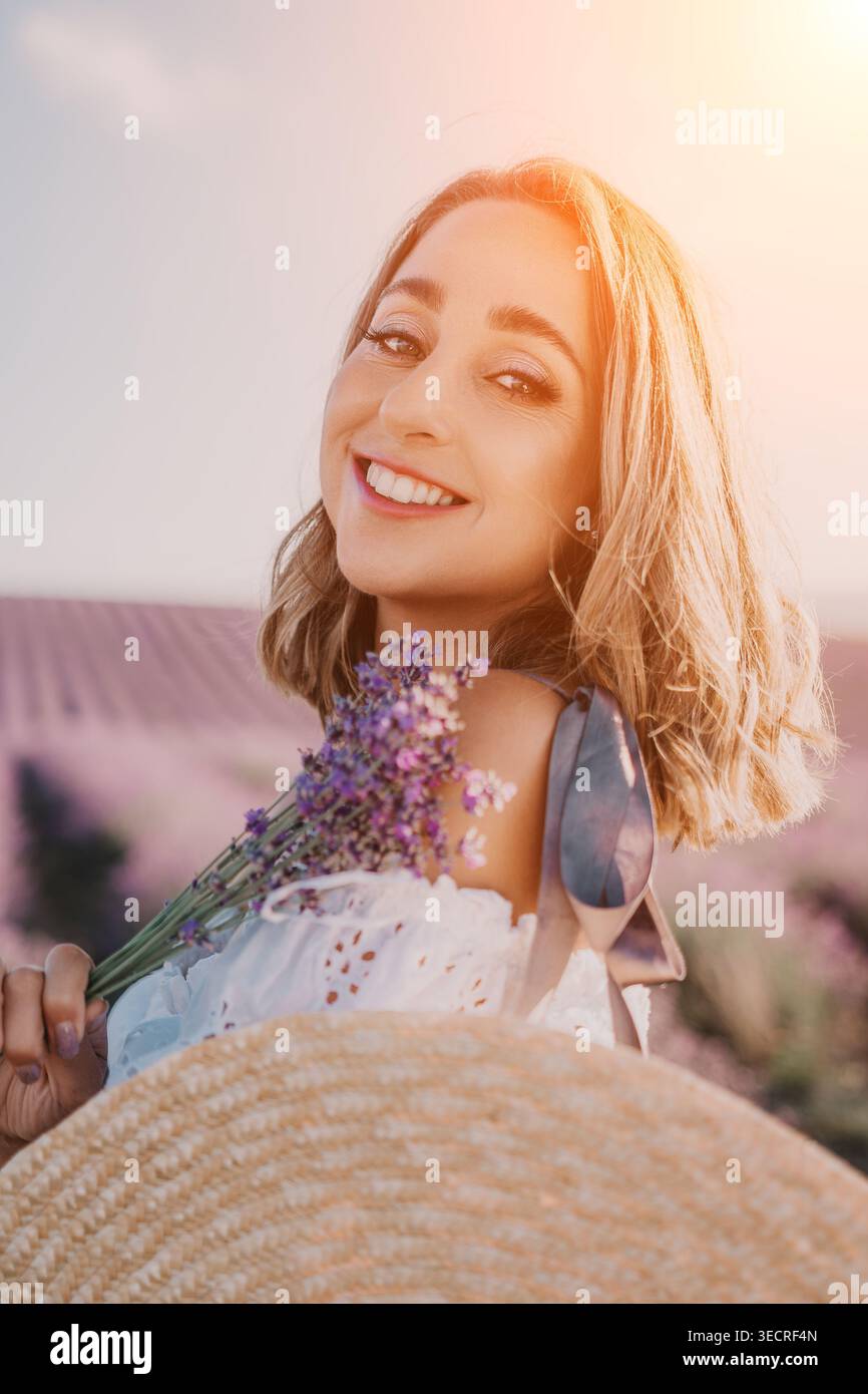 Frau Lavendel Sonnenuntergang lächelnde junge Dame mit frischen Blumen in blühendem lila Feld während der warmen Sommer goldenen Stunde Stockfoto