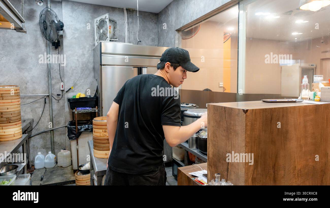 Ein engagierter Küchenchef in einem taiwanesischen Restaurant bereitet frische xiaolongbao-Knödel zu. Die Küche ist voller Aktivität und bietet authentische kulinarische Spezialitäten Stockfoto