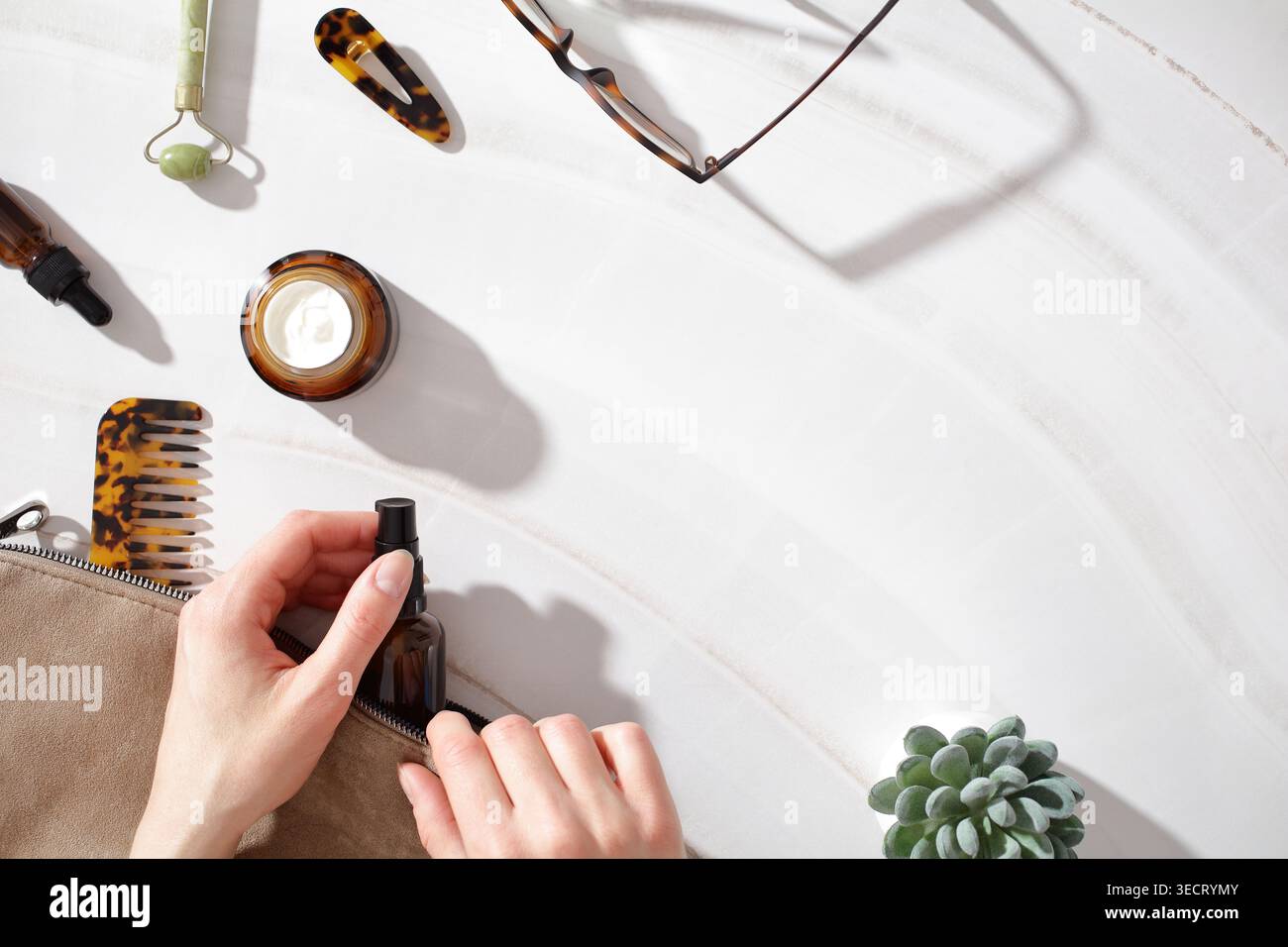Minimaler, flacher Auflagebereich mit Kosmetikflaschen, Kamm und Accessoires auf einer Marmoroberfläche, die an einen ruhigen, langsamen Beauty Morni erinnert Stockfoto
