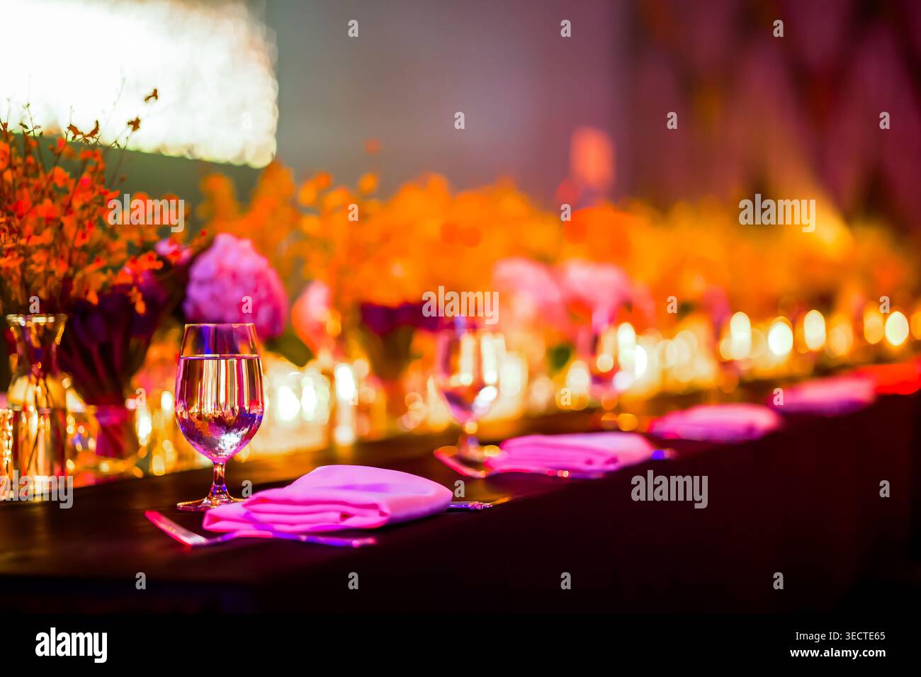 Elegante Gala-Dinner-Tischgarnitur mit rosa und orangefarbenen Blumen an einem Luxus-Hochzeitsempfangsort. Stockfoto