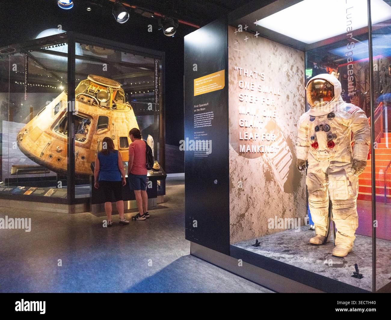 Apollo 11 Command Module Columbia Lunar Space uit Museum Exhibit Washington DC USA | WASHINGTON D.C., Vereinigte Staaten – Besucher studieren das Apollo 11 Command Module Columbia neben Neil Armstrongs Lunar Space uit im National Air and Space Museum. Der von North American Rockwell, Columbia, gebaute 1969 A7L-Anzug, der von ILC Dover aus mehrschichtigem Beta-Tuch und Kapton hergestellt wurde, schützte Armstrong auf der Mondoberfläche. Stockfoto