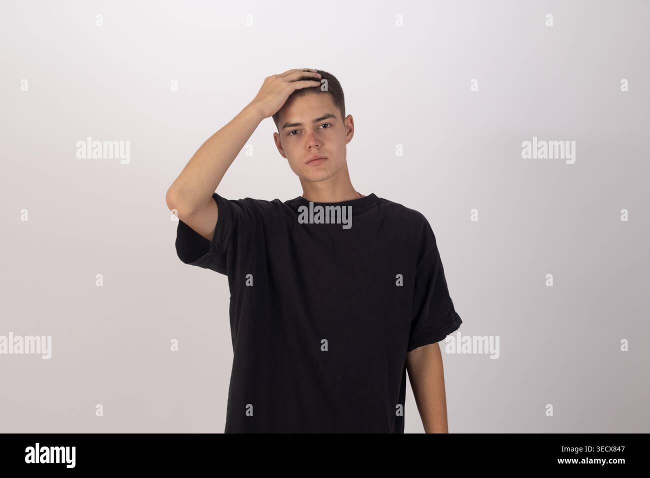 Junger Mann in schwarzem T-Shirt, der seine Stirn berührt Stockfoto