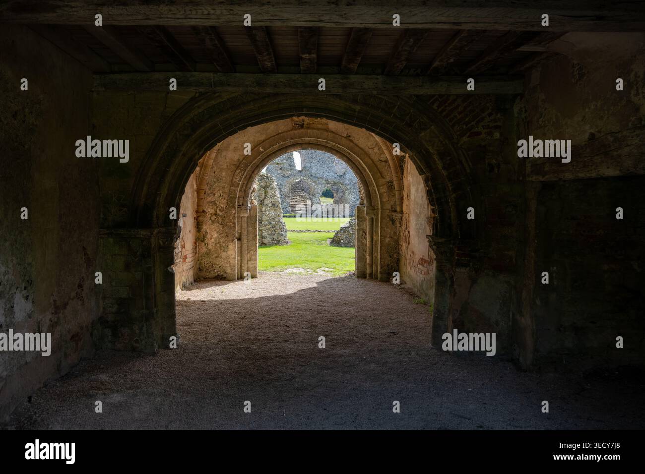 Blick durch einen gewölbten Steinbogen in den Innenhof der Castle Acre Priory Ruinen, Castle Acre, Norfolk, England, Großbritannien. Stockfoto