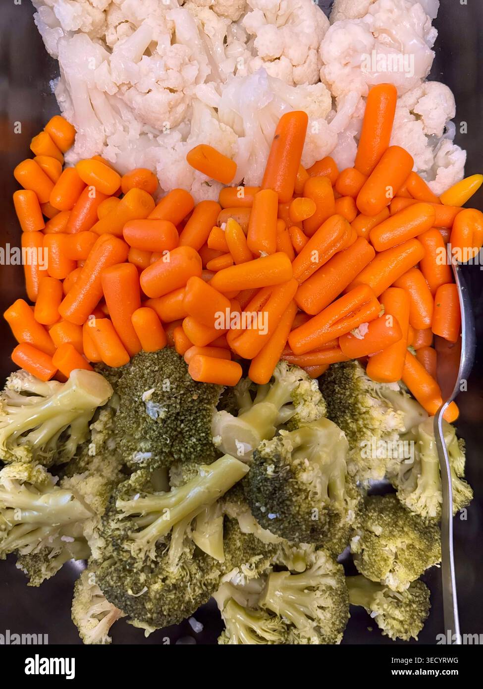 Gedämpftes gemischtes Gemüse mit Brokkoli-Röschen, Baby-Karotten und Blumenkohl auf einem Buffet-Tablett. - Smartphone-aufgenommenes Stockfoto