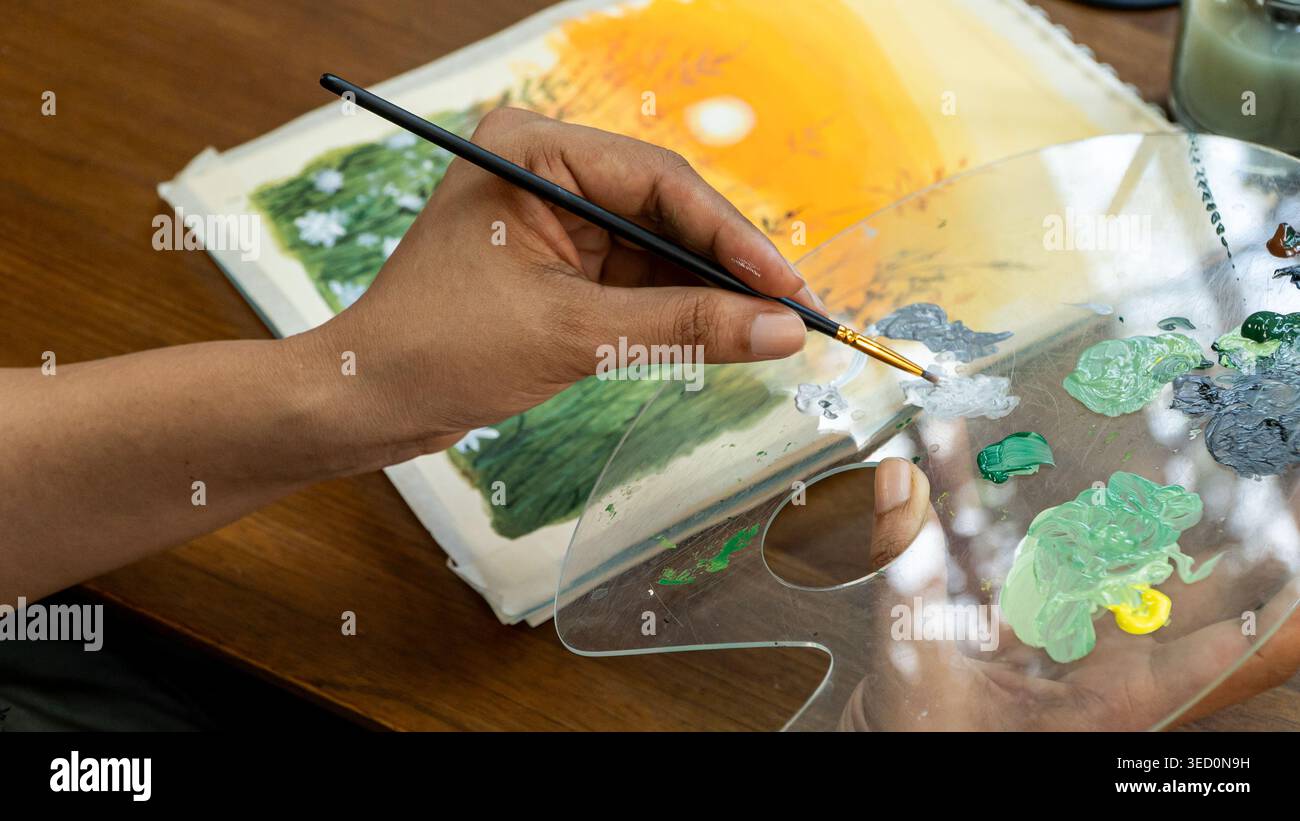 Nahaufnahme einer Frau, die die transparente Palette hält, die Grün- und Weißaquarell vermischt Stockfoto