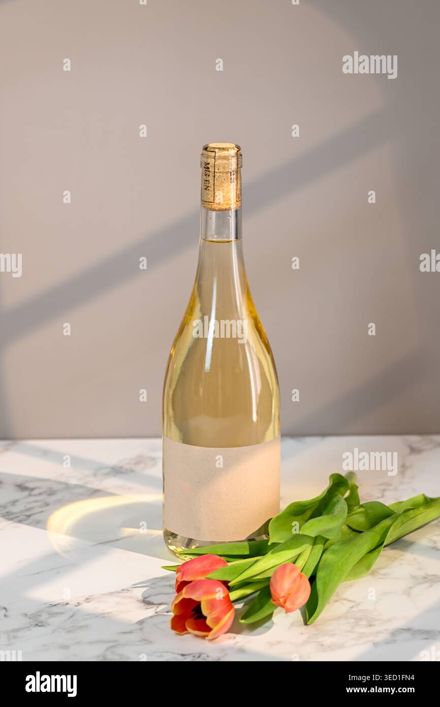 Weißweinflasche neben frischen Tulpen auf der Oberfläche platziert Stockfoto