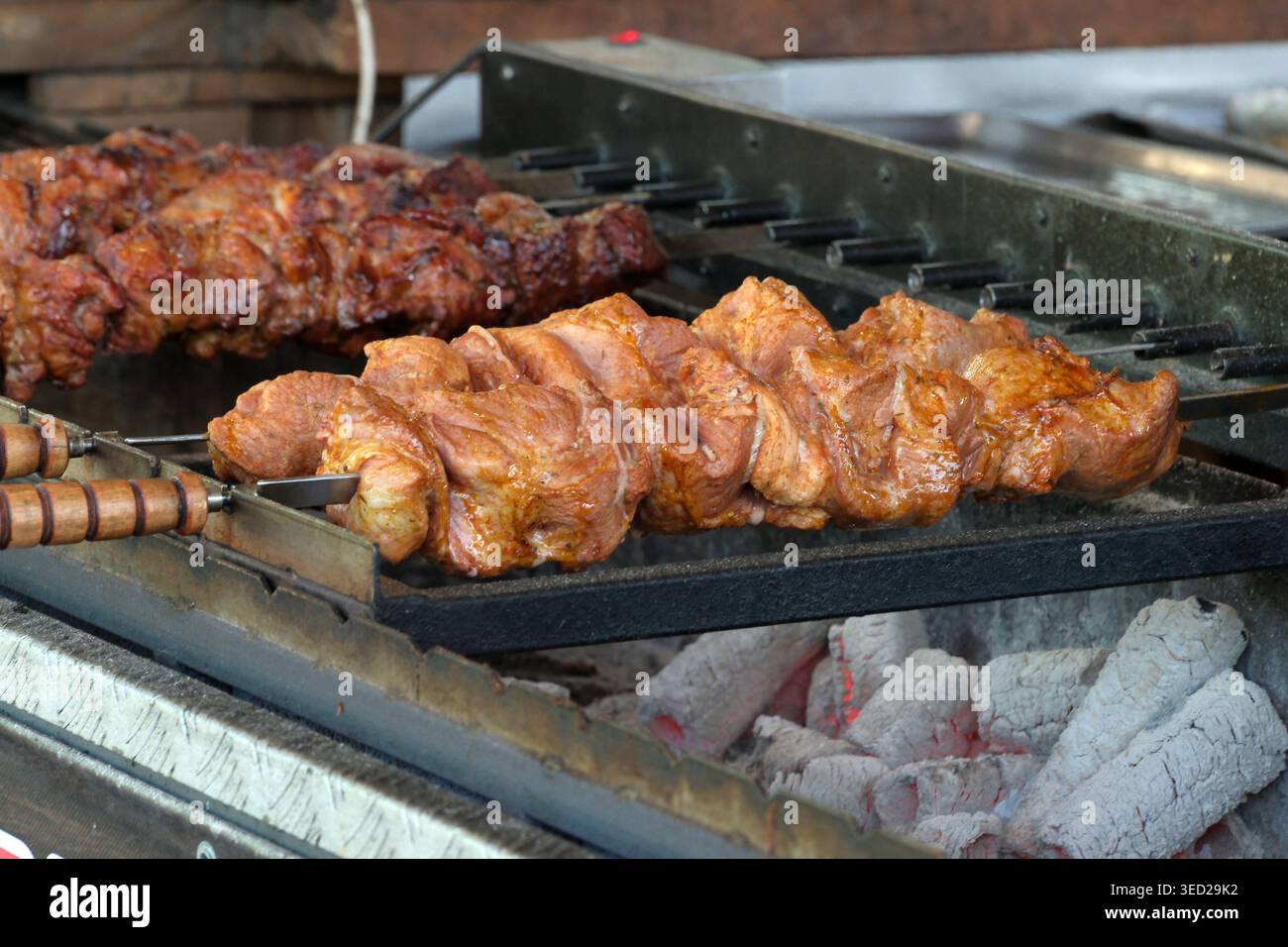 Fleischspieße sickern herrlich über glühenden Kohlen während eines lebhaften Grillens. Stockfoto