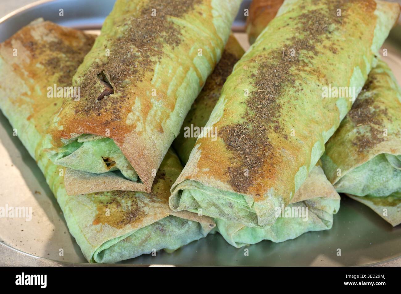 Frisch zubereitete grüne Wraps sind ordentlich gestapelt und bieten lebendige Füllungen und Gewürze. Stockfoto