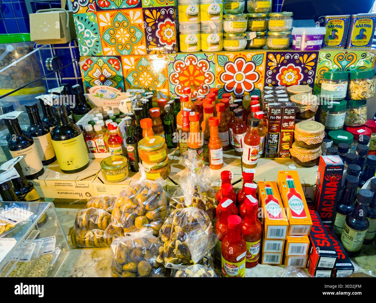 Traditioneller portugiesischer Lebensmittelmarkt mit piri piri Hot Soße Flaschen, getrockneten Feigen und bunten dekorativen Fliesen in einem Einzelhandelsregal Stockfoto