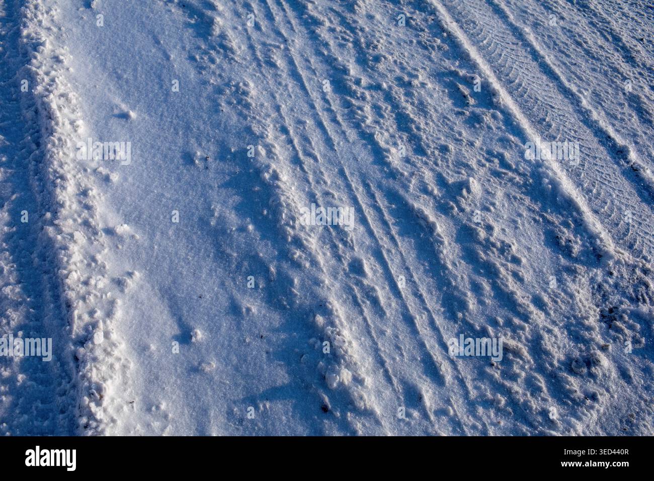 Schneestruktur mit Reifenspuren auf vereister Winterstraße Stockfoto