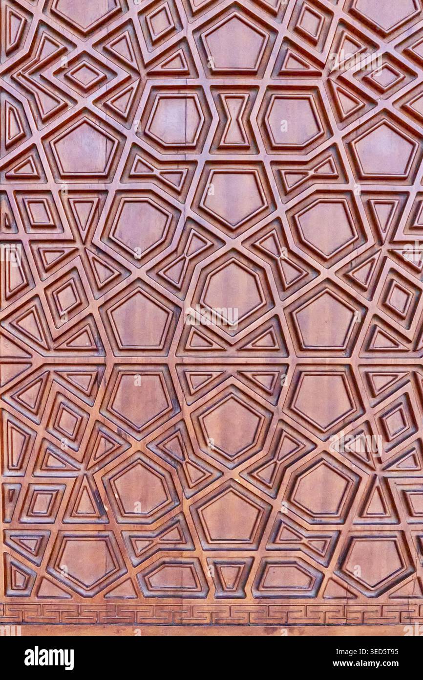 Detaillierte Ansicht eines kunstvoll geschnitzten geometrischen Musters an einer traditionellen Holztür. Islamisches Design, sich wiederholende polygonale Formen und symmetrische Handwerkskunst Stockfoto