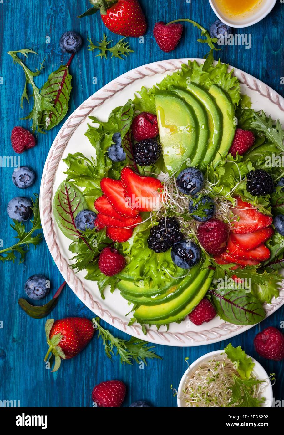 Gemischte Salatblätter mit Beeren, Avocado und Honig-Senf-Dressing Stockfoto
