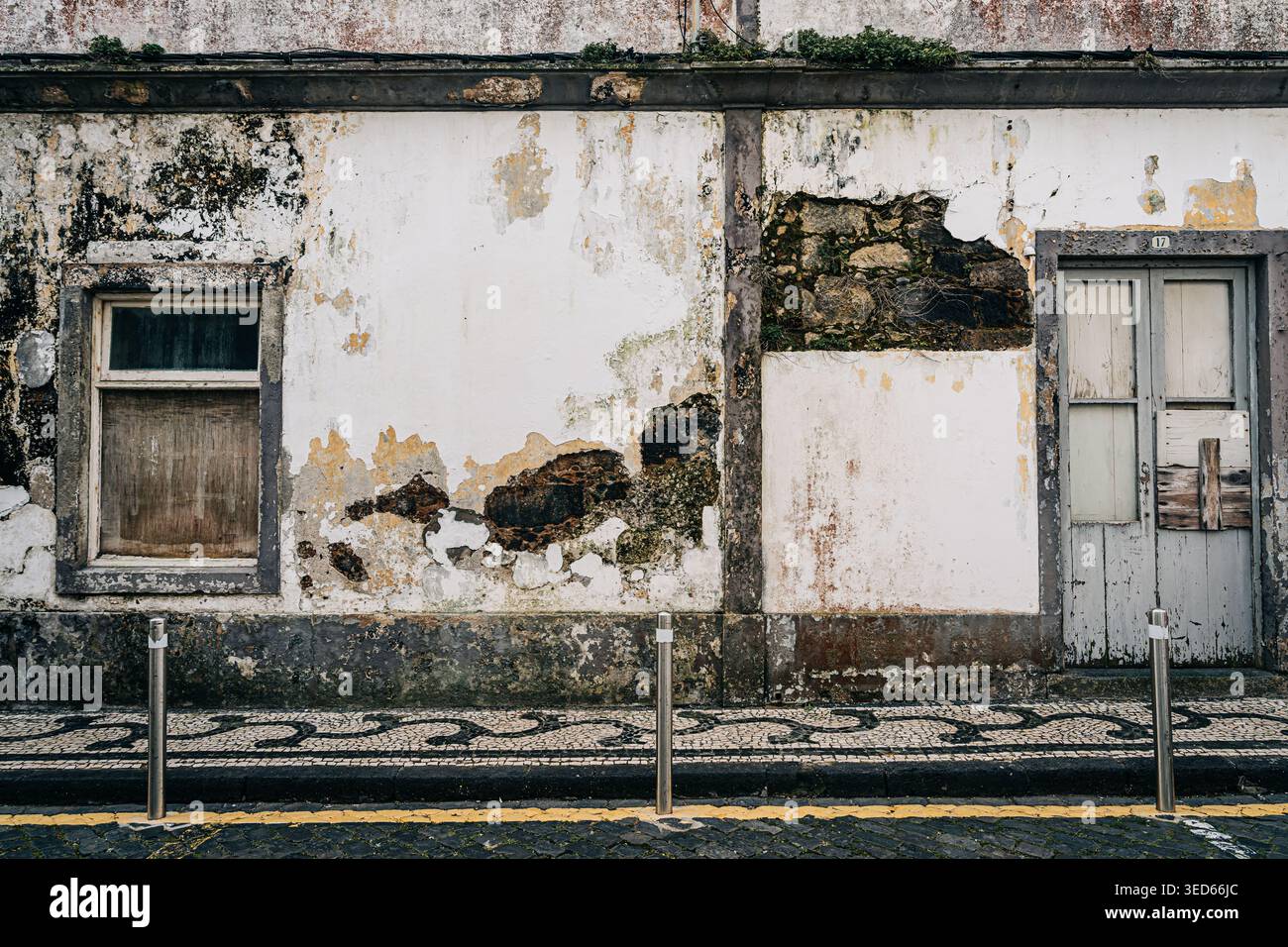 Verwitterte Wand mit abblätternder Farbe, Tür und Fenster Stockfoto