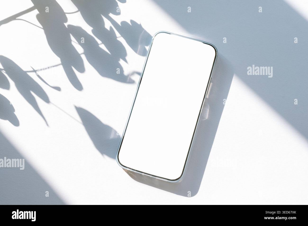 Minimale flache Lage mit Mobiltelefon und hinterlässt Schatten auf weißem Hintergrund. Draufsicht, Modell. Stockfoto