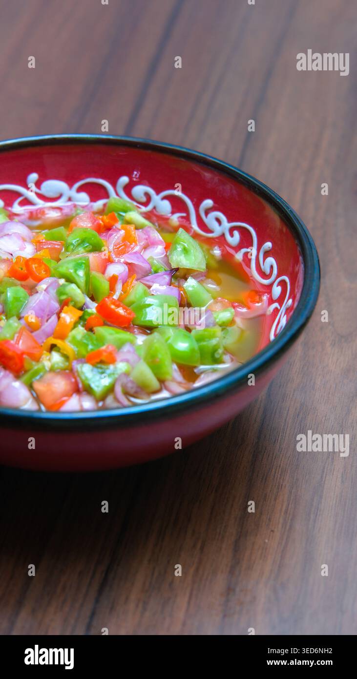 Frische hausgemachte Sambal Matah und Chili-Sauce nach Dabu-Dabu-Art, serviert in einer dekorativen Schüssel mit gehacktem Chili, Schalotten und grünem Gemüse. Stockfoto
