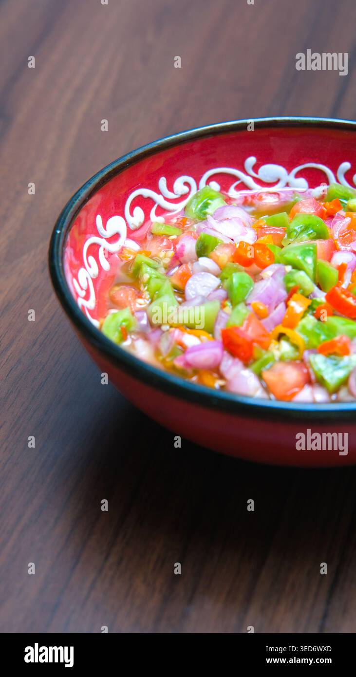 Frische hausgemachte Sambal Matah und Chili-Sauce nach Dabu-Dabu-Art, serviert in einer dekorativen Schüssel mit gehacktem Chili, Schalotten und grünem Gemüse. Stockfoto