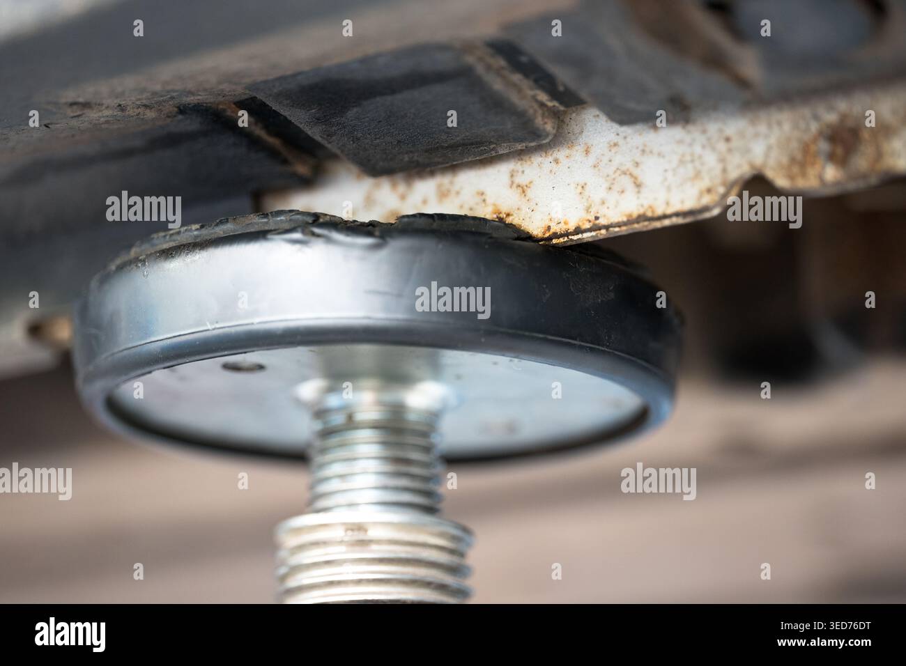 Technische Aufnahme eines mechanischen Wagenhebers, der ein Fahrzeug zur Wartung oder Reparatur am Fahrgestellpunkt anhebt Stockfoto