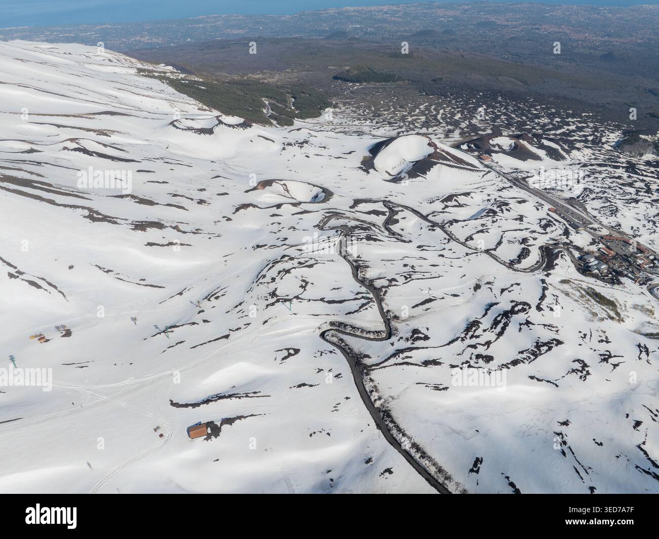 Aus der Vogelperspektive auf die Versante Sud dell' Ätna mit schneebedeckten Vulkankratern und gewundenen Bergstraßen in Nicolosi, Sizilien, Italien. Stockfoto