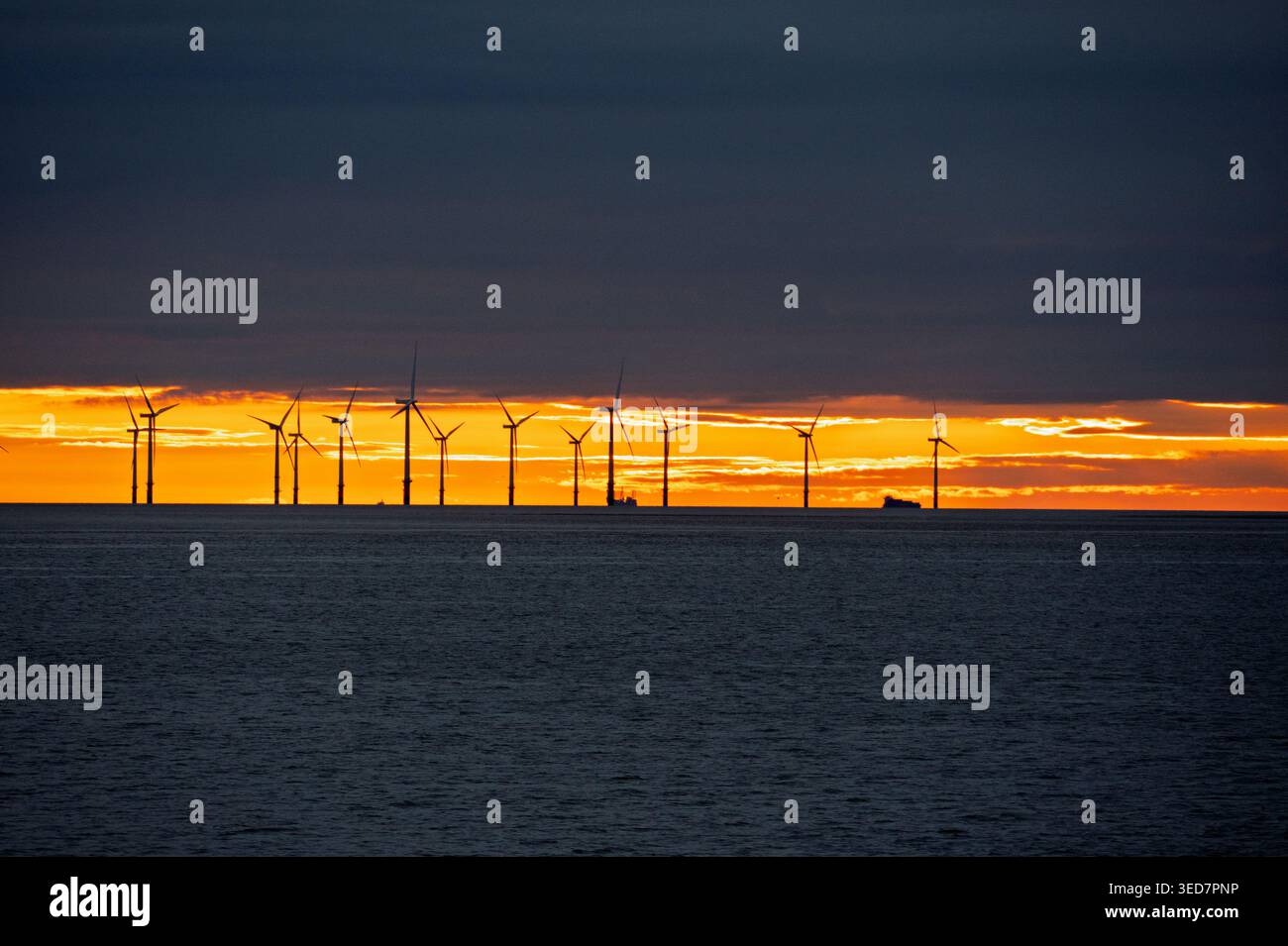 Ein dunkler orangefarbener Himmel hinter den Windparks von Liverpool in der Liverpool Bay an der Mündung des Flusses Mersey. Stockfoto
