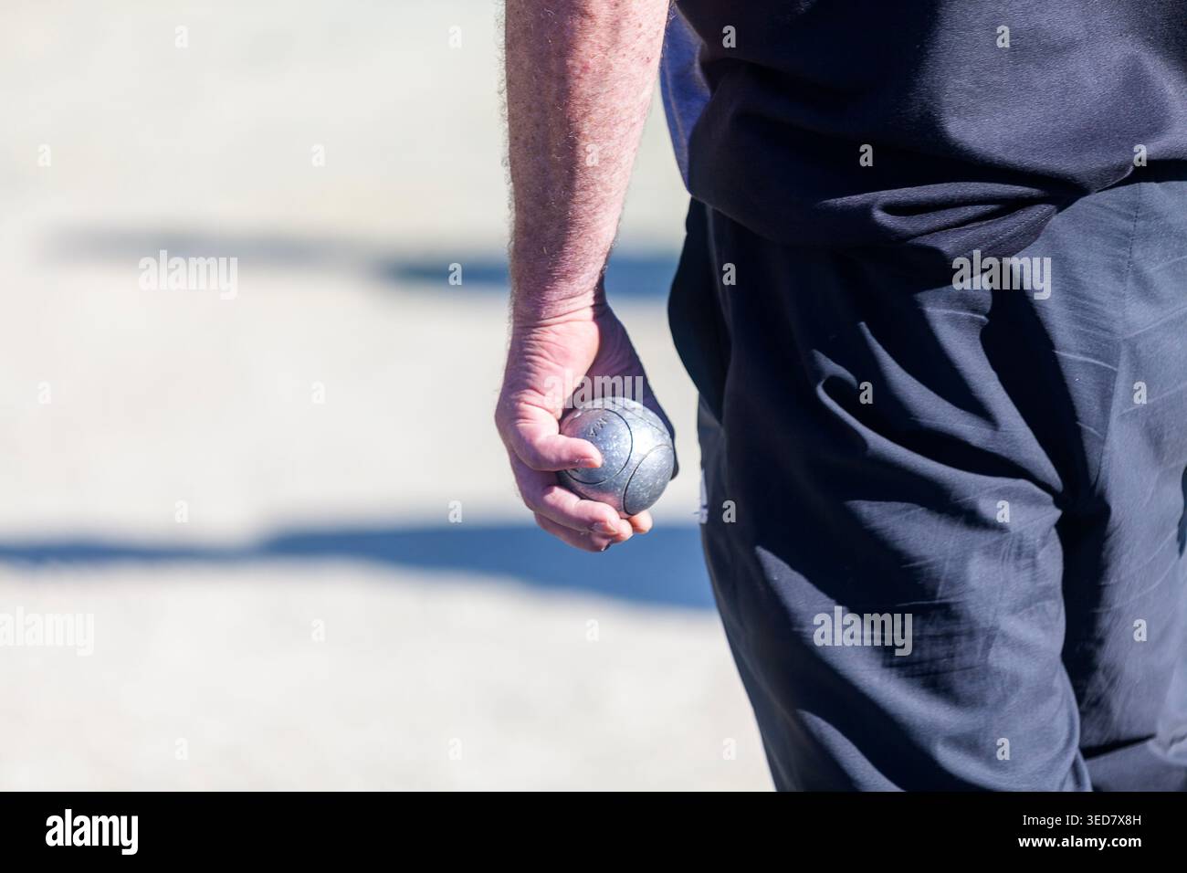 Pétanque-Spieler mit einer Boule in der Hand, die darauf wartet, dass er an der Reihe ist. Stockfoto