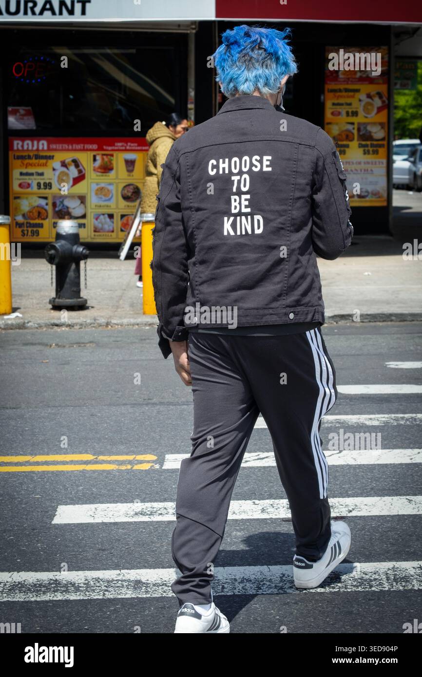 WÄHLEN SIE, FREUNDLICH ZU SEIN. Aufmunternde Worte auf dem Rücken eines blauhaarigen Jungen Windbreakers. Auf der 37th Avenue in Jackson Heights, Queens, New York. Stockfoto