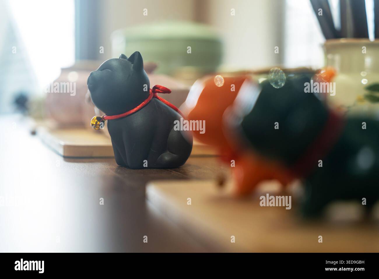 Diese niedliche schwarze Katzenfigur verfügt über eine glänzende Keramikoberfläche und einen roten Kragen mit einer winzigen Glocke, was sie zu einem bezaubernden Schmuckstück für jedes Heim macht Stockfoto