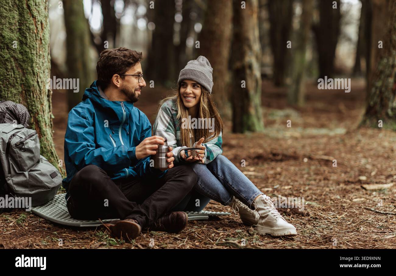 Glückliche junge europäische Touristen in Jacken mit Rucksack im Wald Camping, genießen Sie die kalte Jahreszeit Stockfoto