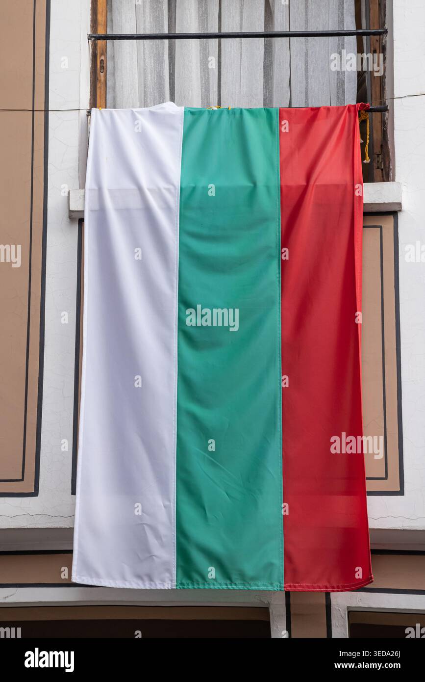 Plovdiv, Bulgarien. Die bulgarische Flagge hängt vor einem Fenster. Stockfoto