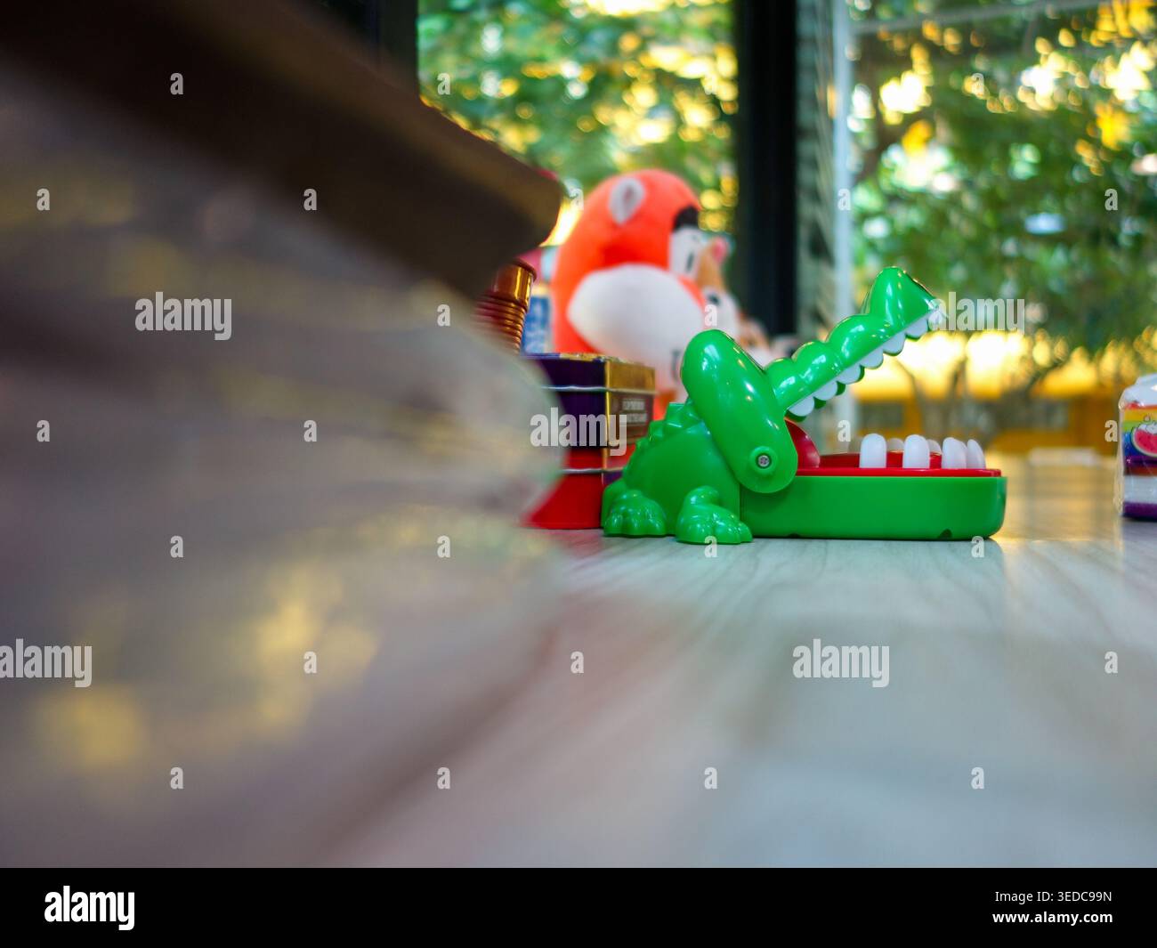 Ein leuchtend grünes Krokodil-Spielzeug auf einem Holztisch fängt den Geist des Kinderspiels und der Fantasie ein und eignet sich perfekt für die Unterhaltung von Kindern im Haus. Stockfoto