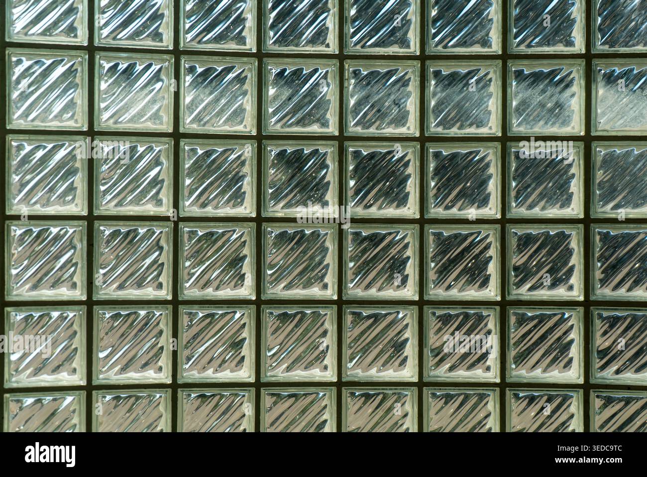 Nahaufnahme einer Glasblockwand mit strukturierten Mustern und Reflexionen. Dieses Designelement optimiert die Innenräume mit Licht und Elk Stockfoto