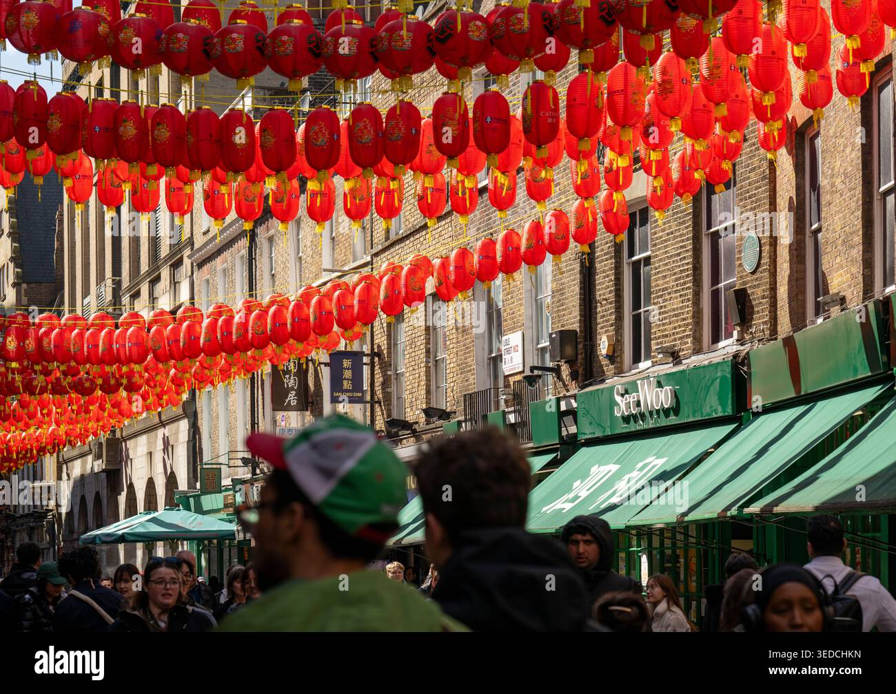 Menschenmassen laufen unter Reihen traditioneller roter Laternen in Chinatown, Soho, London, Großbritannien Stockfoto