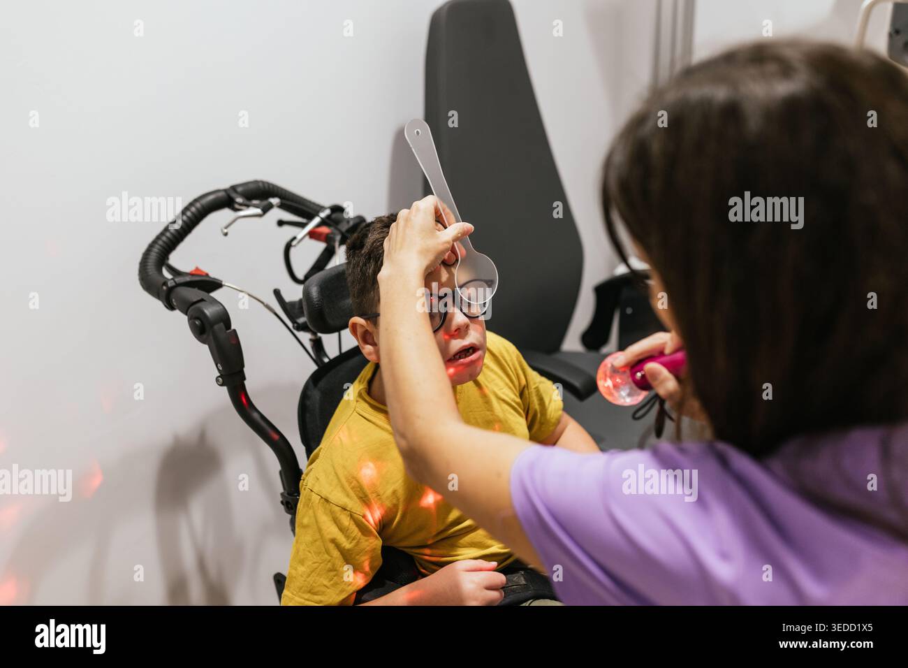 Augenoptiker bei der Augenuntersuchung von Kindern mit Zerebralparese im Rollstuhl Stockfoto