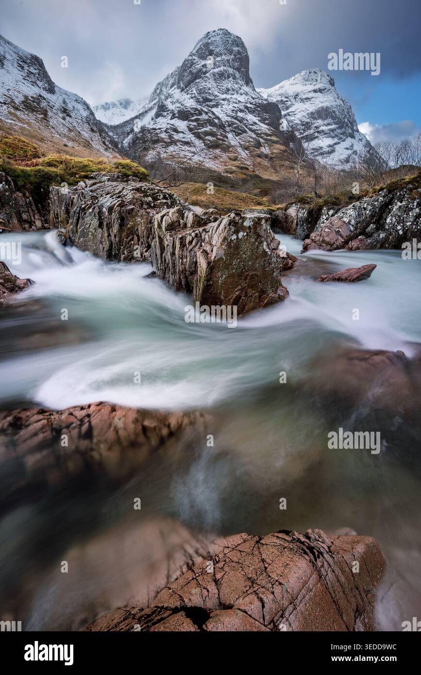 Fließendes Wasser am River Coe mit atemberaubendem Blick auf die legendäre Three Sisters Bergkette in Glencoe, Schottland, Großbritannien. Stockfoto