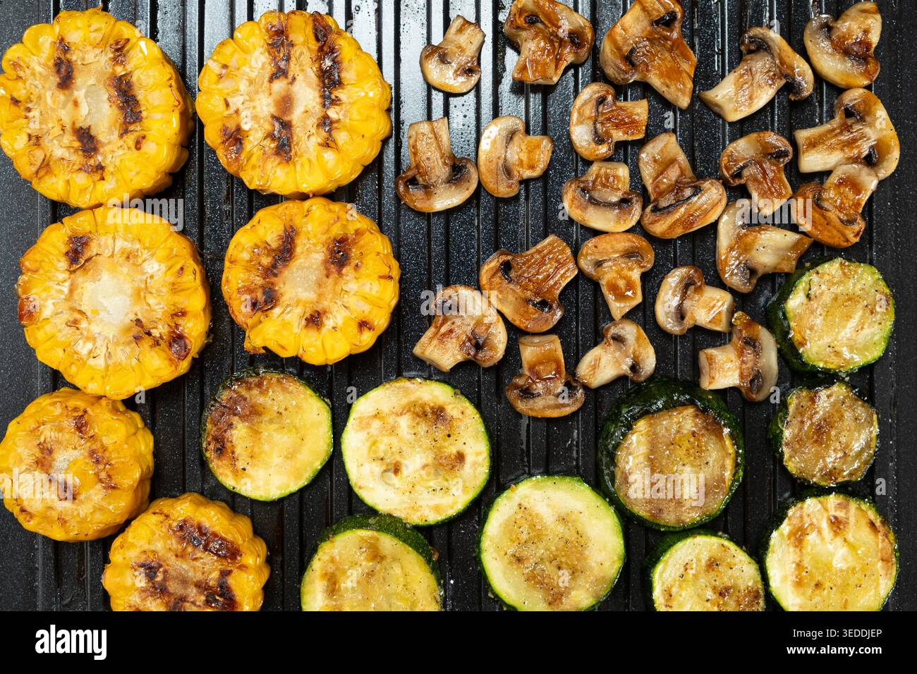 Kochen Sie Mais, Zucchini und Pilze zusammen auf einer Grillplatte Stockfoto
