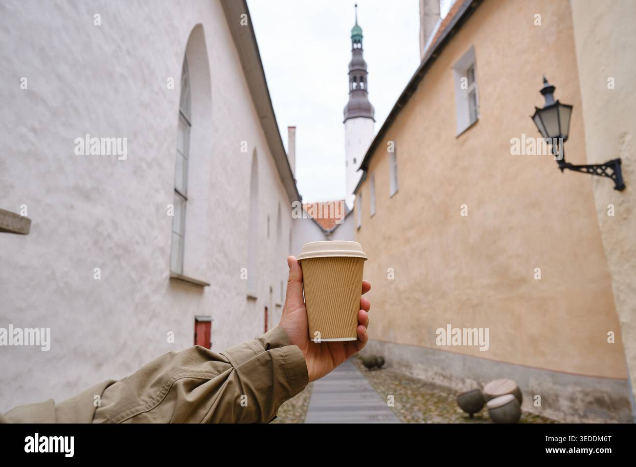 Hand hält eine Einweg-Kaffeetasse in einer modernen europäischen Stadtstraße Stockfoto