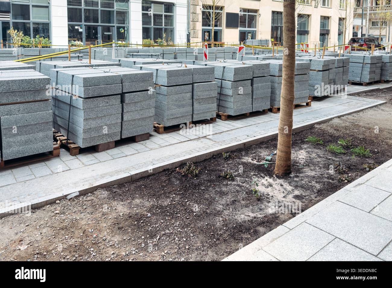 Große Stapel von Granitpflasterplatten befinden sich auf Holzpaletten auf der städtischen Straßenbaustelle. Granitpflasterplatten, Steinpflasterinstallation, Schüttgut Stockfoto