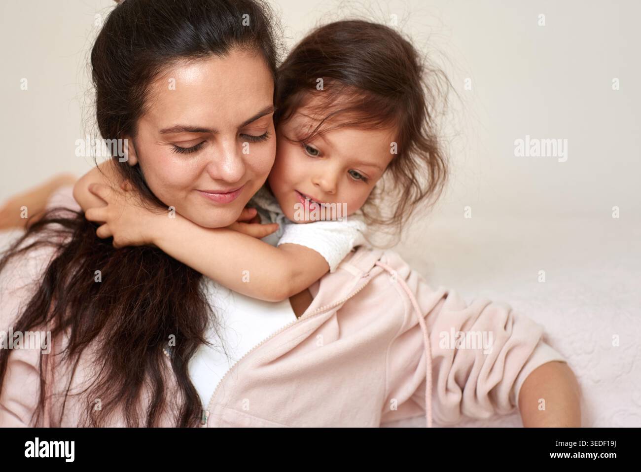 Mutter fühlt sich geliebt, während ihre Tochter sie von hinten umarmt und starke familiäre Verbindung und Zärtlichkeit zeigt Stockfoto